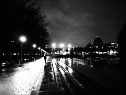 black and white image of a rainy street in a city lit by streetlights