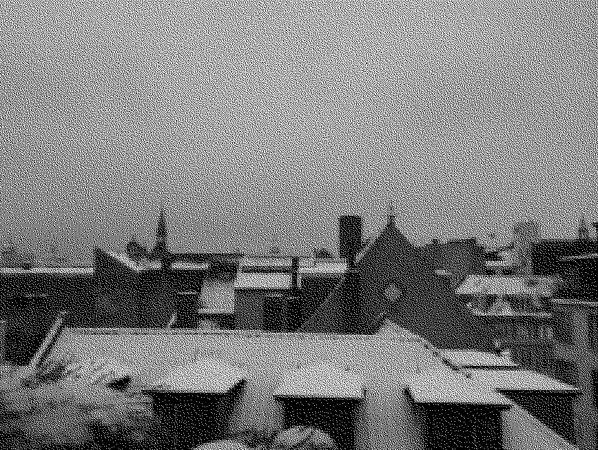 Black and white view from a rooftop showing the tops of buildings covered in snow